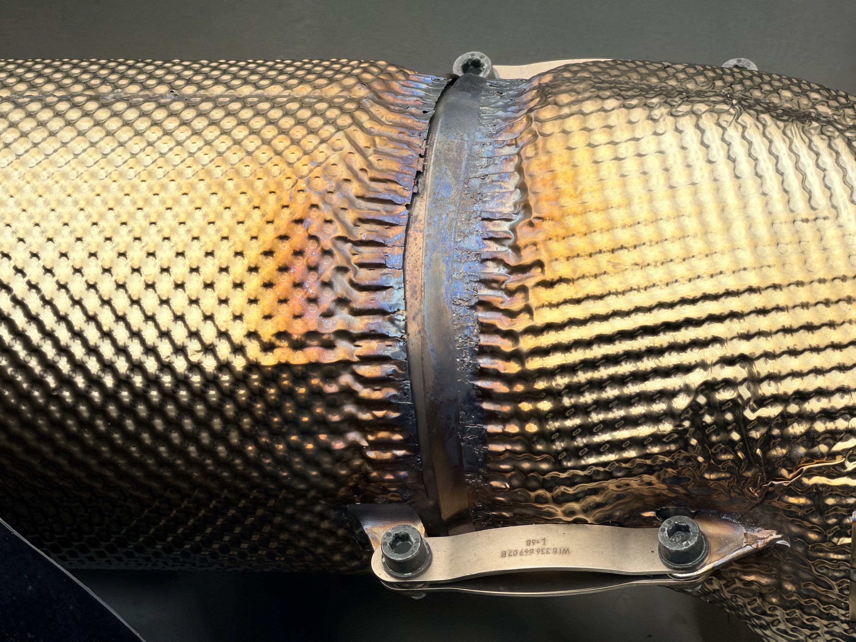 Ducting from the engine of a race car that looks mostly new but with the color beginning to change from heat around a seam